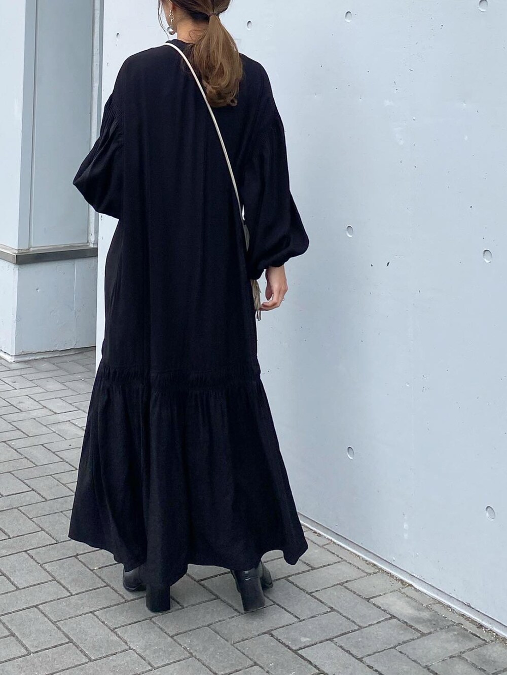 ブラック系のブーツ、ブラック系のワンピース、ホワイト系のショルダーバッグを着用したレディースの秋コーディネートの3枚目の写真