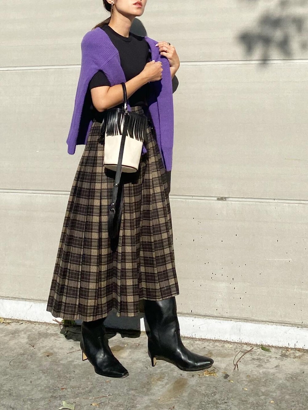 グレー系のスカート、ブラック系のブーツ、ホワイト系のバッグを着用したレディースの秋コーディネートの3枚目の写真