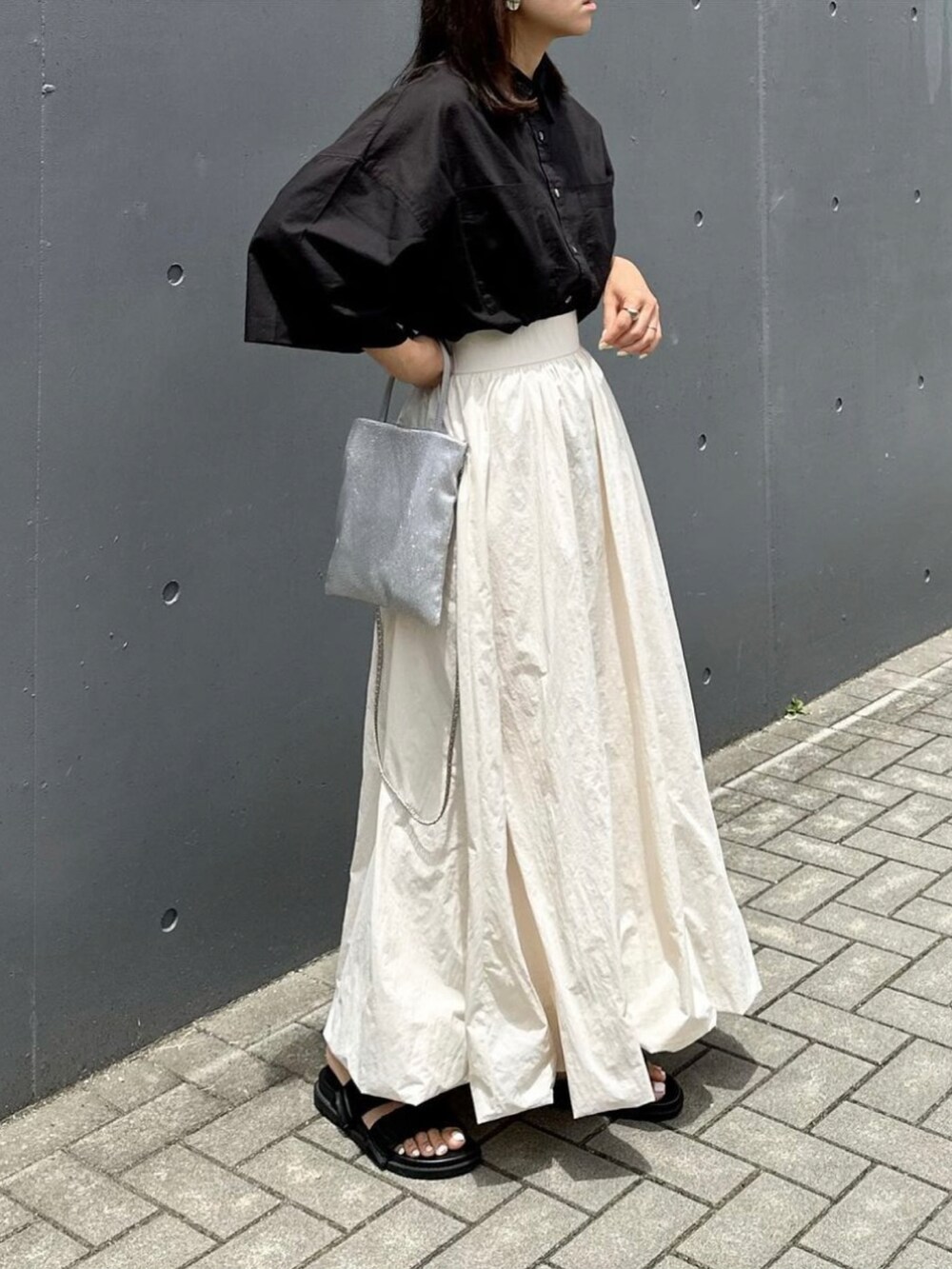 ホワイト系のスカート、ブラック系のシャツ/ブラウス、ブラック系のサンダルを着用したレディースの夏コーディネートの2枚目の写真