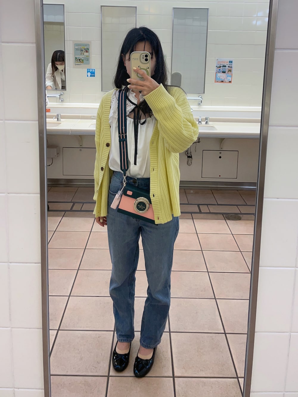 イエロー系のカーディガン/ボレロ、ピンク系のトートバッグ、ブルー系のデニムパンツを着用したレディースの春コーディネートの2枚目の写真