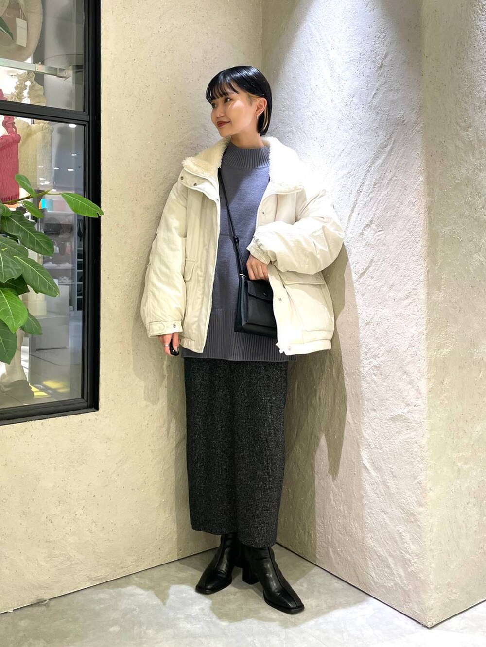 ブラック系のショルダーバッグ、ブルー系のニット/セーター、ブラック系のパンプスを着用したレディースの冬コーディネートの3枚目の写真