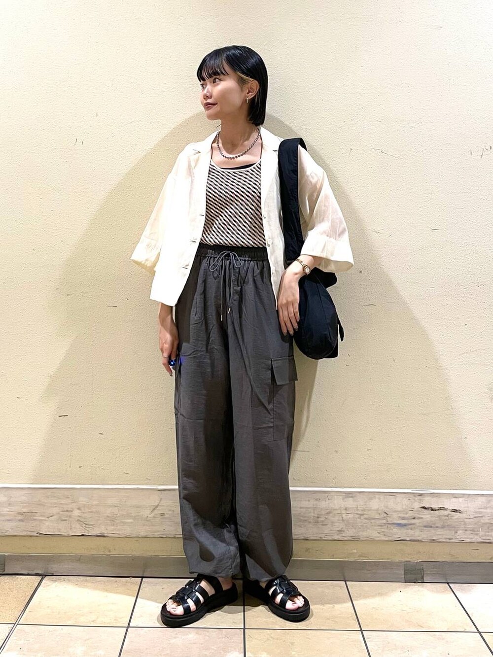 ホワイト系のシャツ/ブラウス、グレー系のカーゴパンツ、ブラック系のスニーカーを着用したレディースの夏コーディネートの3枚目の写真
