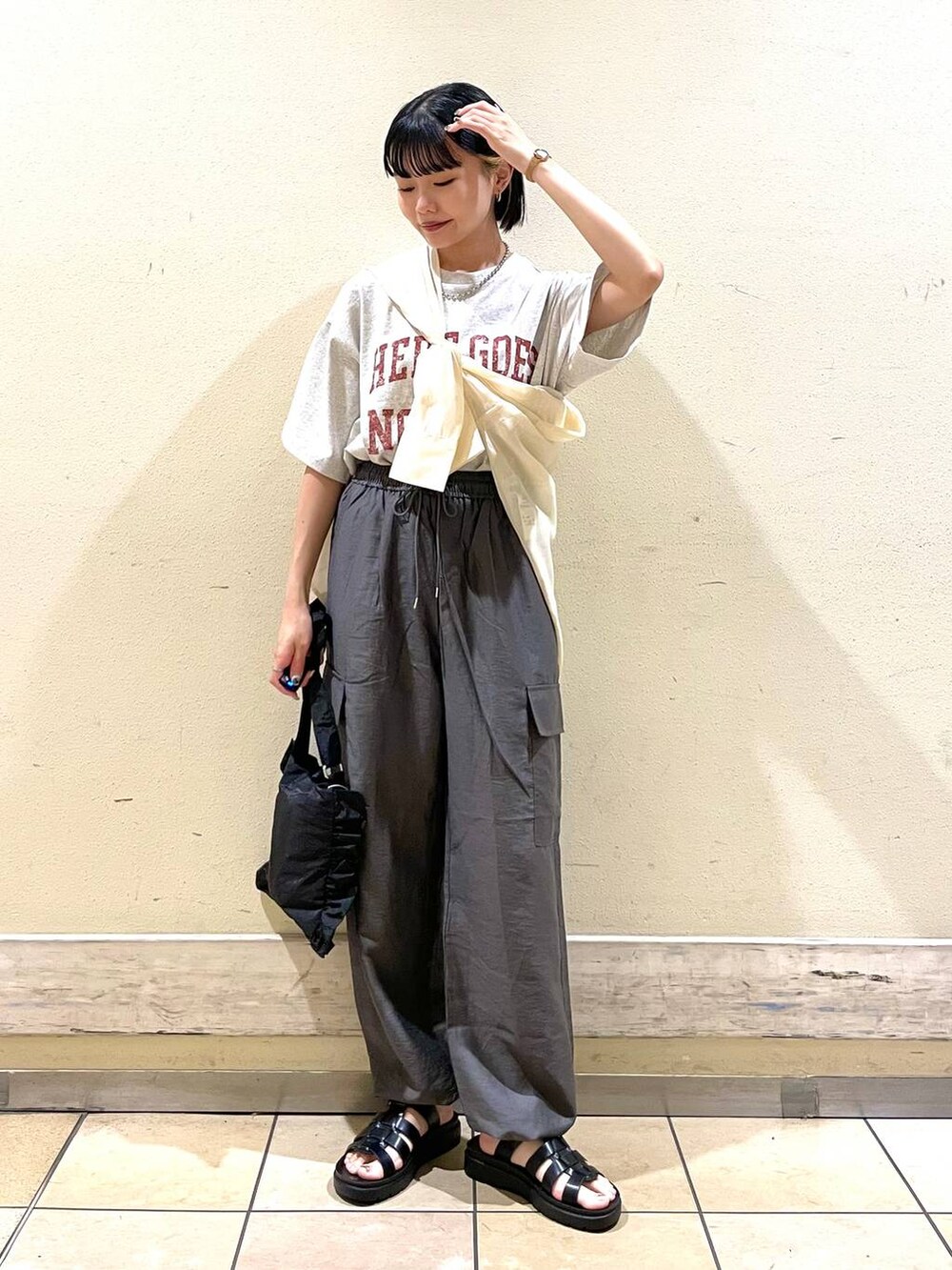 グレー系のカーゴパンツ、グレー系のTシャツ/カットソー、ブラック系のスニーカーを着用したレディースの夏コーディネートの3枚目の写真