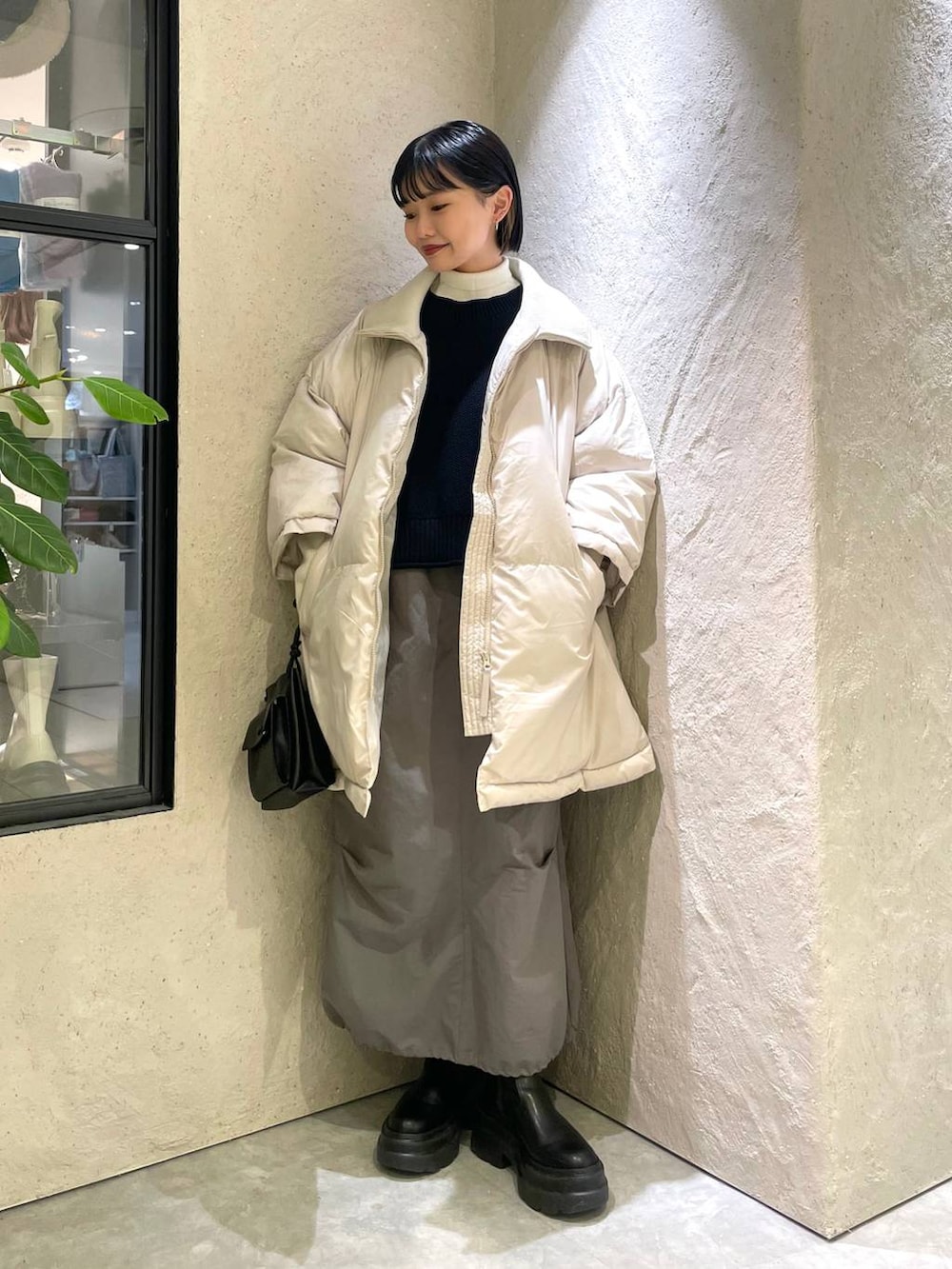 ブラック系のショルダーバッグ、ホワイト系のポンチョ、ホワイト系のニット/セーターを着用したレディースの冬コーディネートの3枚目の写真