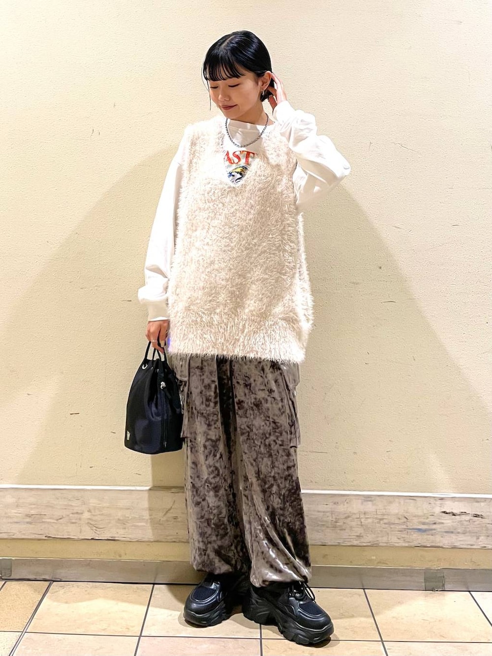 ホワイト系のTシャツ/カットソー、ホワイト系のベスト、ブラック系のスニーカーを着用したレディースの秋コーディネートの3枚目の写真