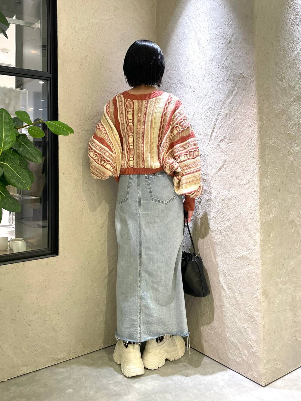 ベージュ系のニット/セーター、ホワイト系のスニーカー、ブルー系のスカートを着用したレディースの春コーディネートの2枚目の写真
