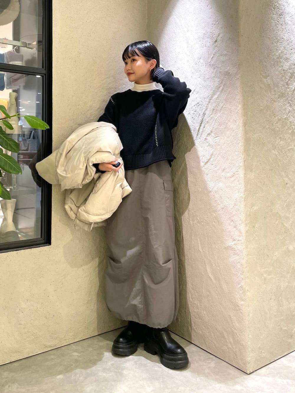 ブラック系のショルダーバッグ、ホワイト系のポンチョ、ホワイト系のニット/セーターを着用したレディースの冬コーディネートの4枚目の写真