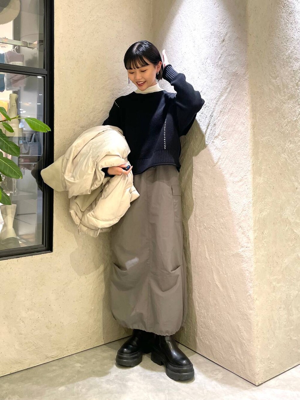 ブラック系のショルダーバッグ、ホワイト系のポンチョ、ホワイト系のニット/セーターを着用したレディースの冬コーディネートの5枚目の写真