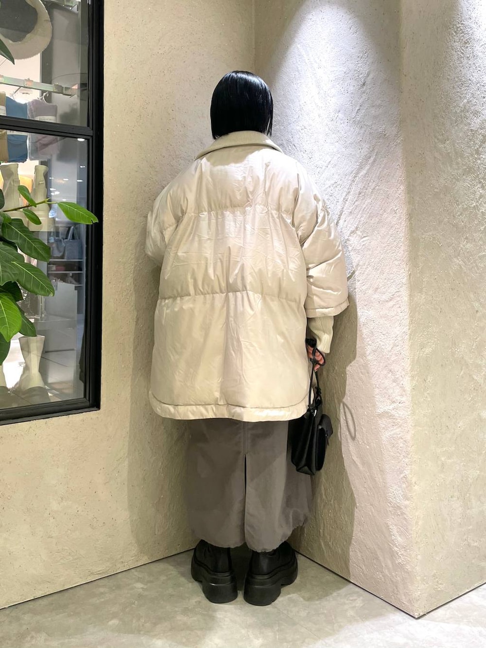 ブラック系のショルダーバッグ、ホワイト系のポンチョ、ホワイト系のニット/セーターを着用したレディースの冬コーディネートの2枚目の写真