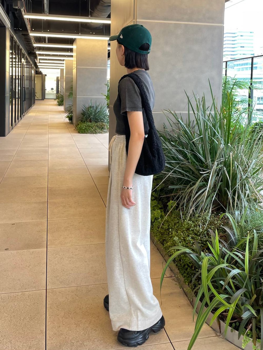 グレー系のスウェットパンツ、ブラック系のハンドバッグ、ブラック系のスニーカーを着用したレディースの夏コーディネートの2枚目の写真