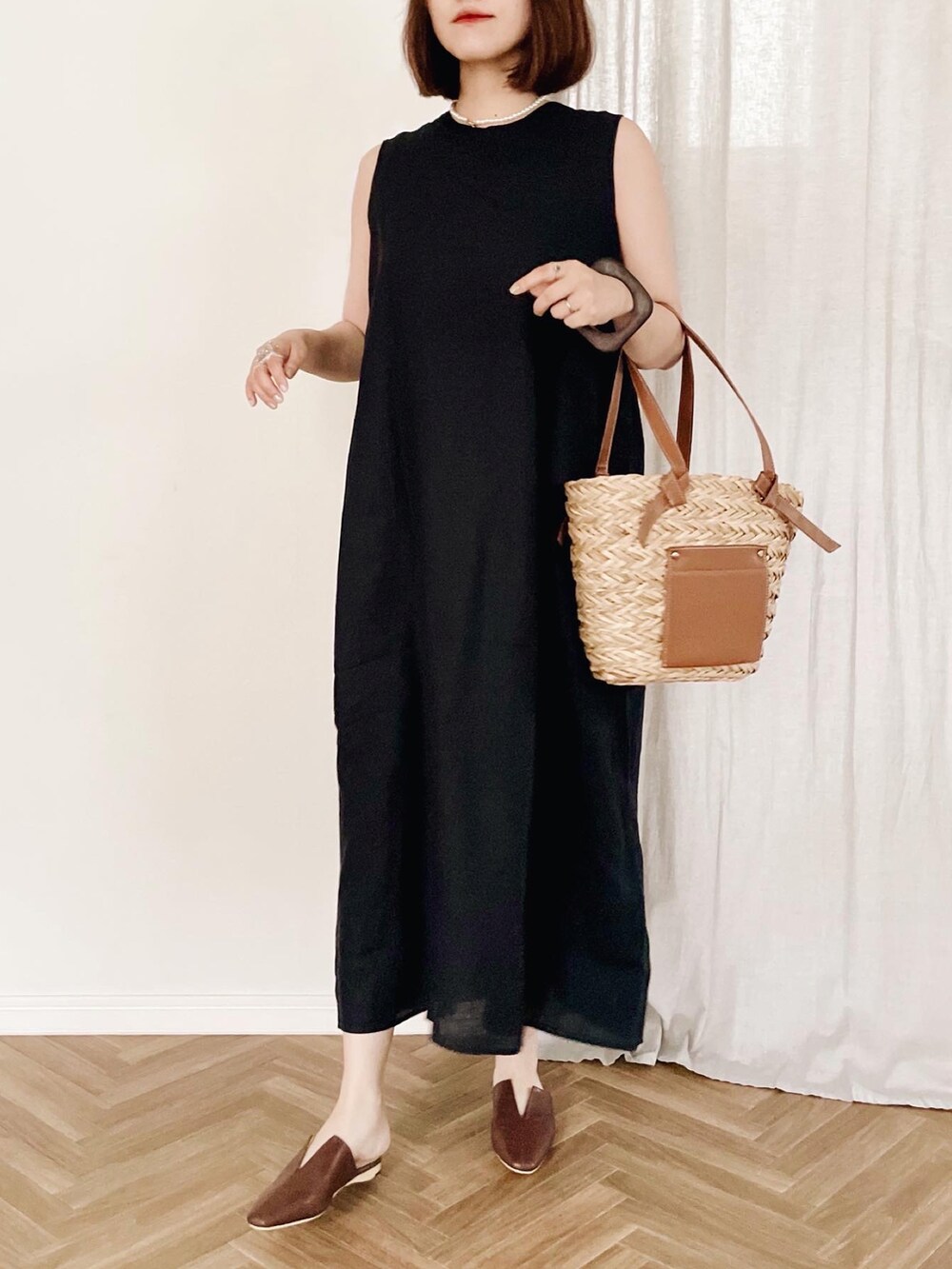 ブラック系のドレス、ブラウン系のかごバッグを着用したレディースの夏コーディネートの2枚目の写真