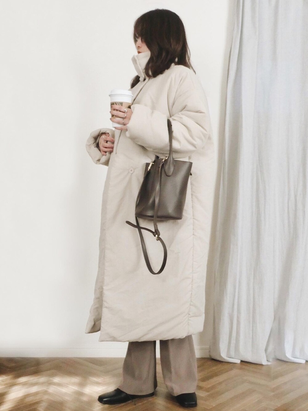 ベージュ系のTシャツ/カットソー、ベージュ系のダウンジャケット/コート、ブラウン系のトートバッグを着用したレディースの冬コーディネートの2枚目の写真