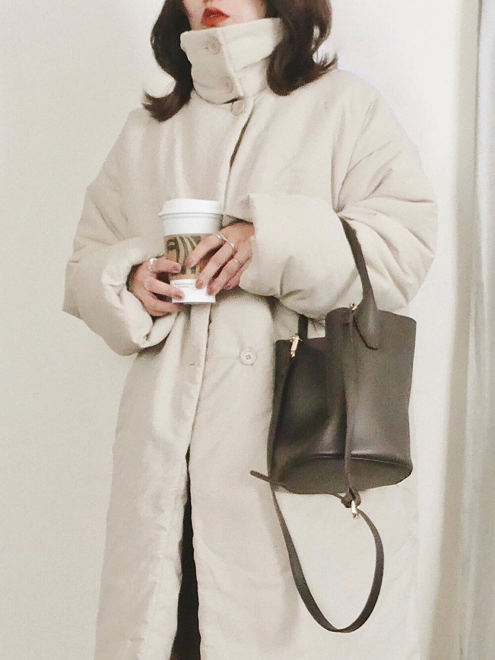 ベージュ系のTシャツ/カットソー、ベージュ系のダウンジャケット/コート、ブラウン系のトートバッグを着用したレディースの冬コーディネートの3枚目の写真