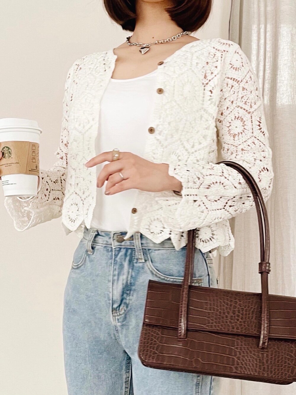 ブルー系のデニムパンツ、ブラウン系のショルダーバッグ、ホワイト系のカーディガン/ボレロを着用したレディースの夏コーディネートの3枚目の写真