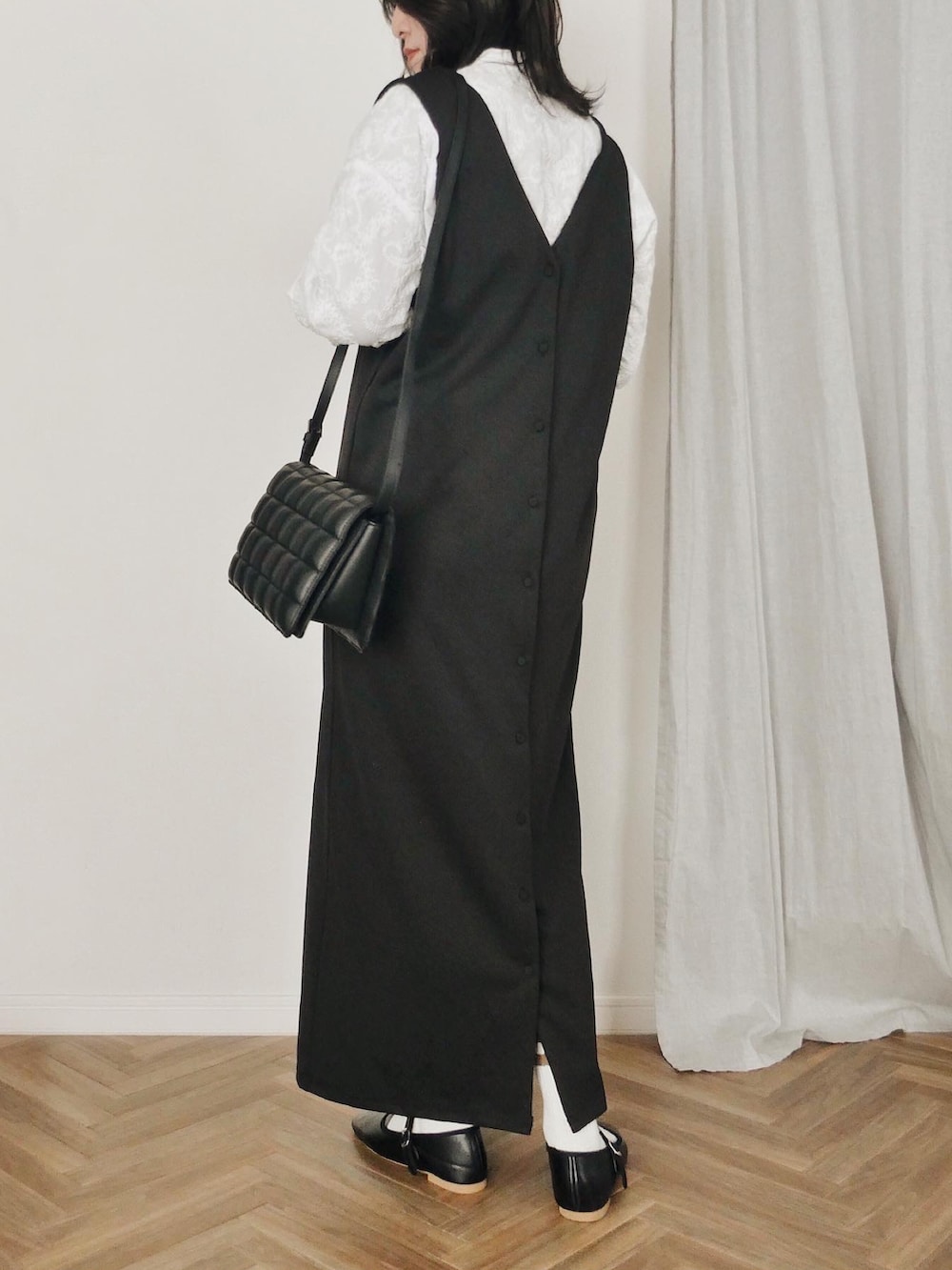 ブラック系のジャンパースカート、ブラック系のバレエシューズ、ホワイト系のシャツ/ブラウスを着用したレディースの冬コーディネートの2枚目の写真