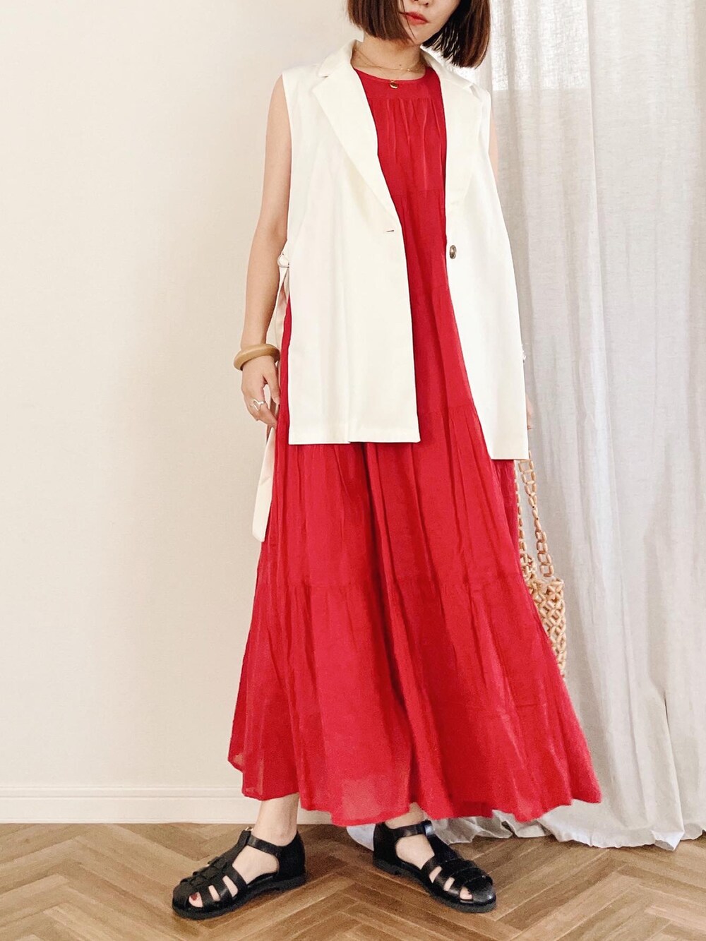 ホワイト系のベスト、ベージュ系のトートバッグ、レッド系のワンピースを着用したレディースの夏コーディネートの3枚目の写真
