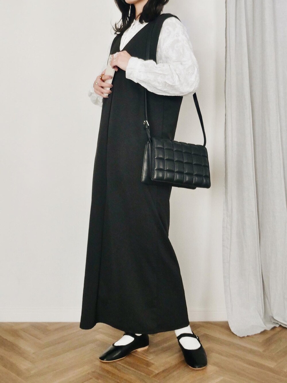 ブラック系のジャンパースカート、ブラック系のバレエシューズ、ホワイト系のシャツ/ブラウスを着用したレディースの冬コーディネートの3枚目の写真