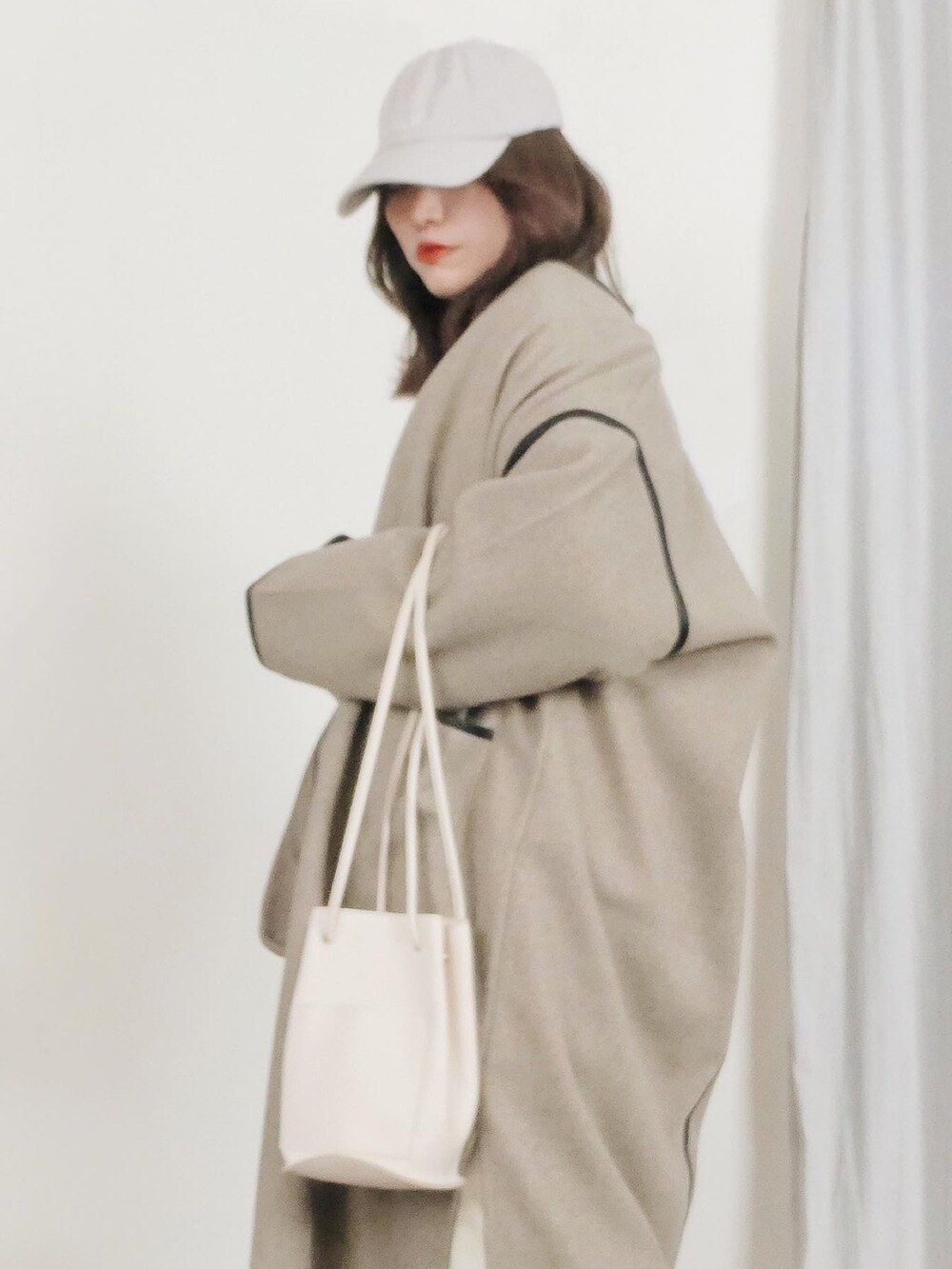 ホワイト系のハンドバッグ、ホワイト系のスニーカー、ホワイト系のニット/セーターを着用したレディースの冬コーディネートの2枚目の写真