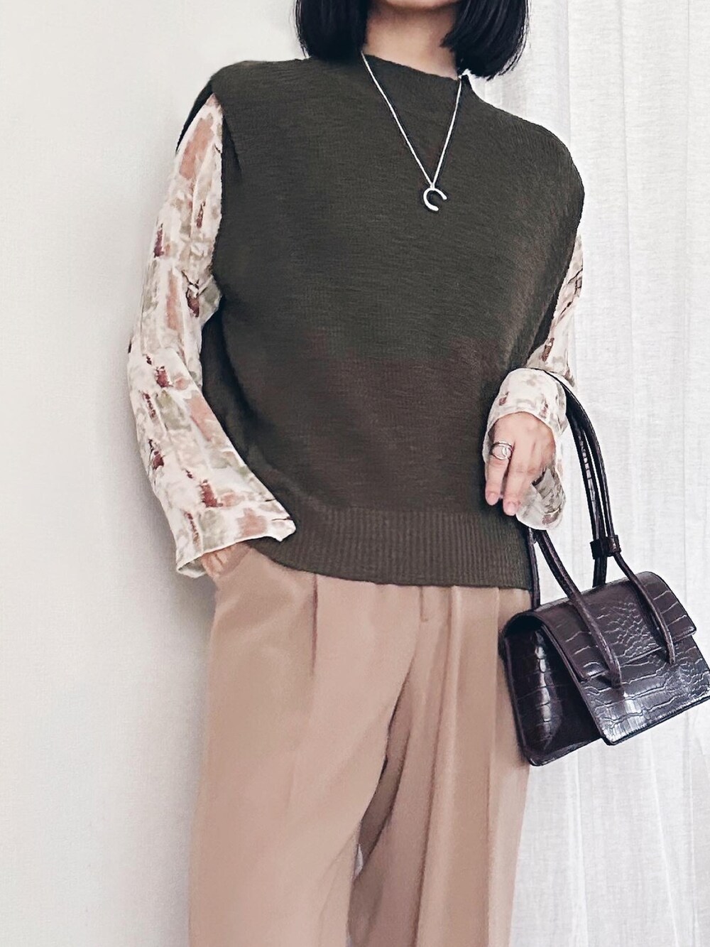 グリーン系のベスト、ブラウン系のショルダーバッグを着用したレディースの秋コーディネートの2枚目の写真