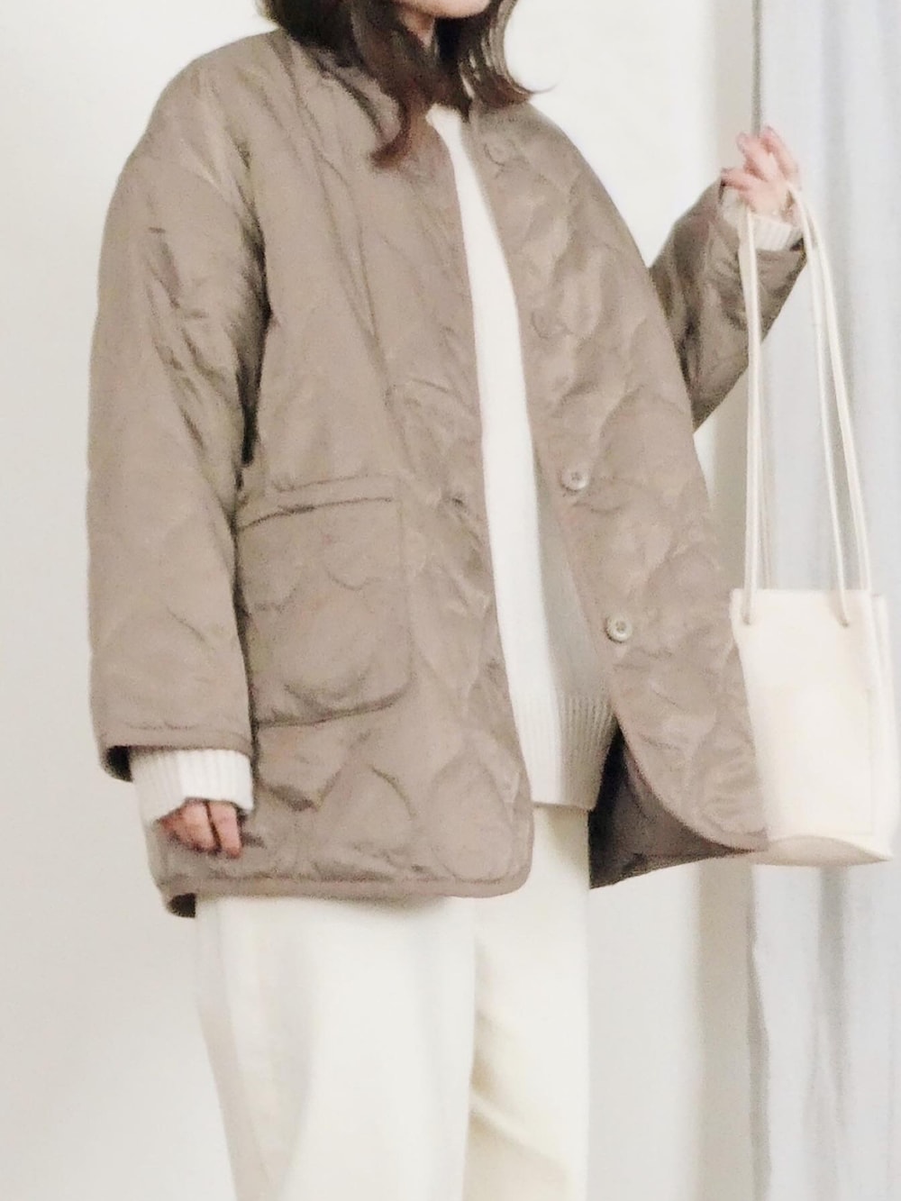 ホワイト系のハンドバッグ、ホワイト系のスニーカー、ホワイト系のニット/セーターを着用したレディースの冬コーディネートの3枚目の写真