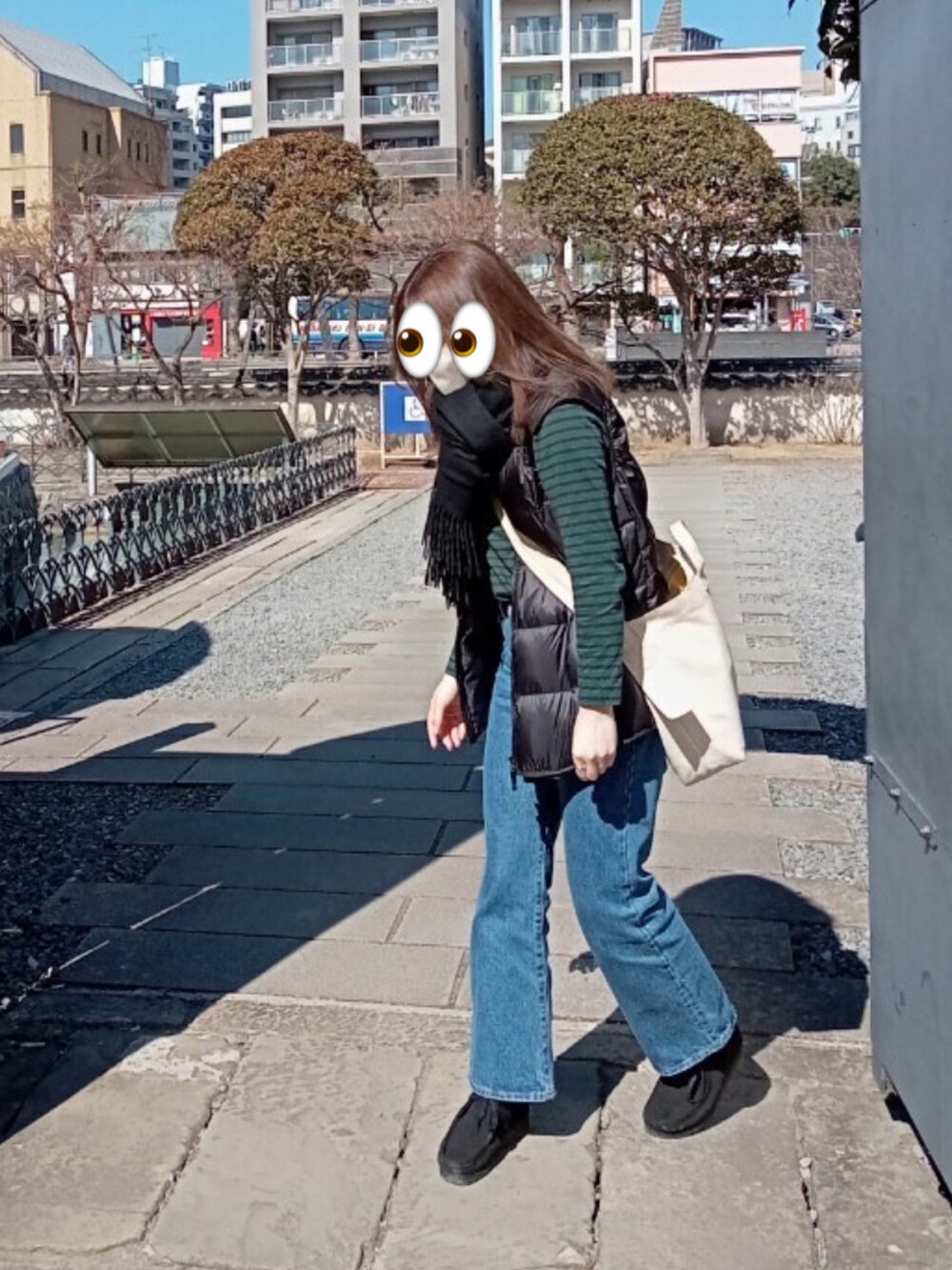 ブルー系のデニムパンツ、ブラック系のダウンベスト、グリーン系のTシャツ/カットソーを着用したレディースの春コーディネートの2枚目の写真