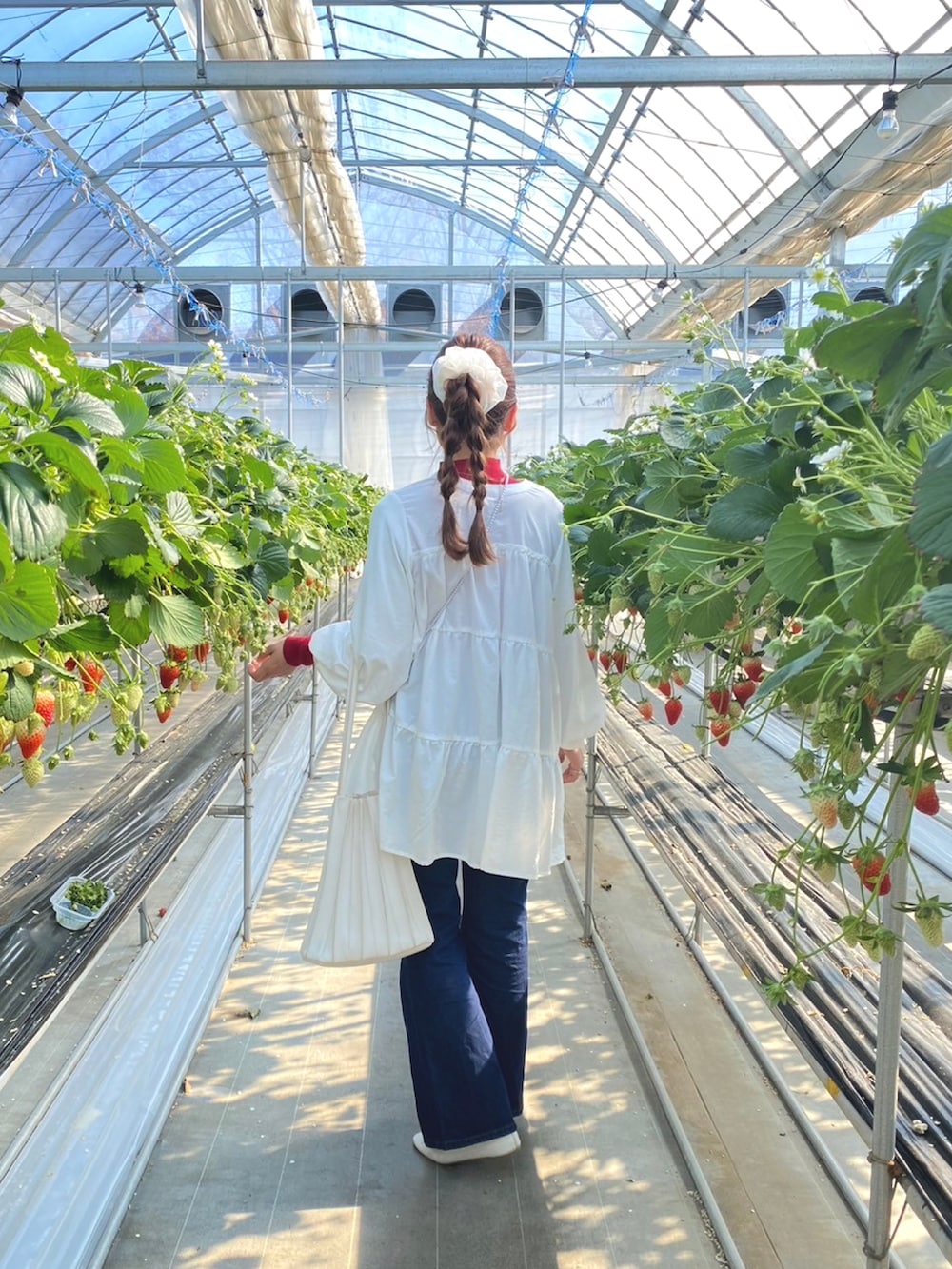 ブルー系のデニムパンツ、ホワイト系のトートバッグ、ホワイト系のワンピースを着用したレディースの冬コーディネートの2枚目の写真