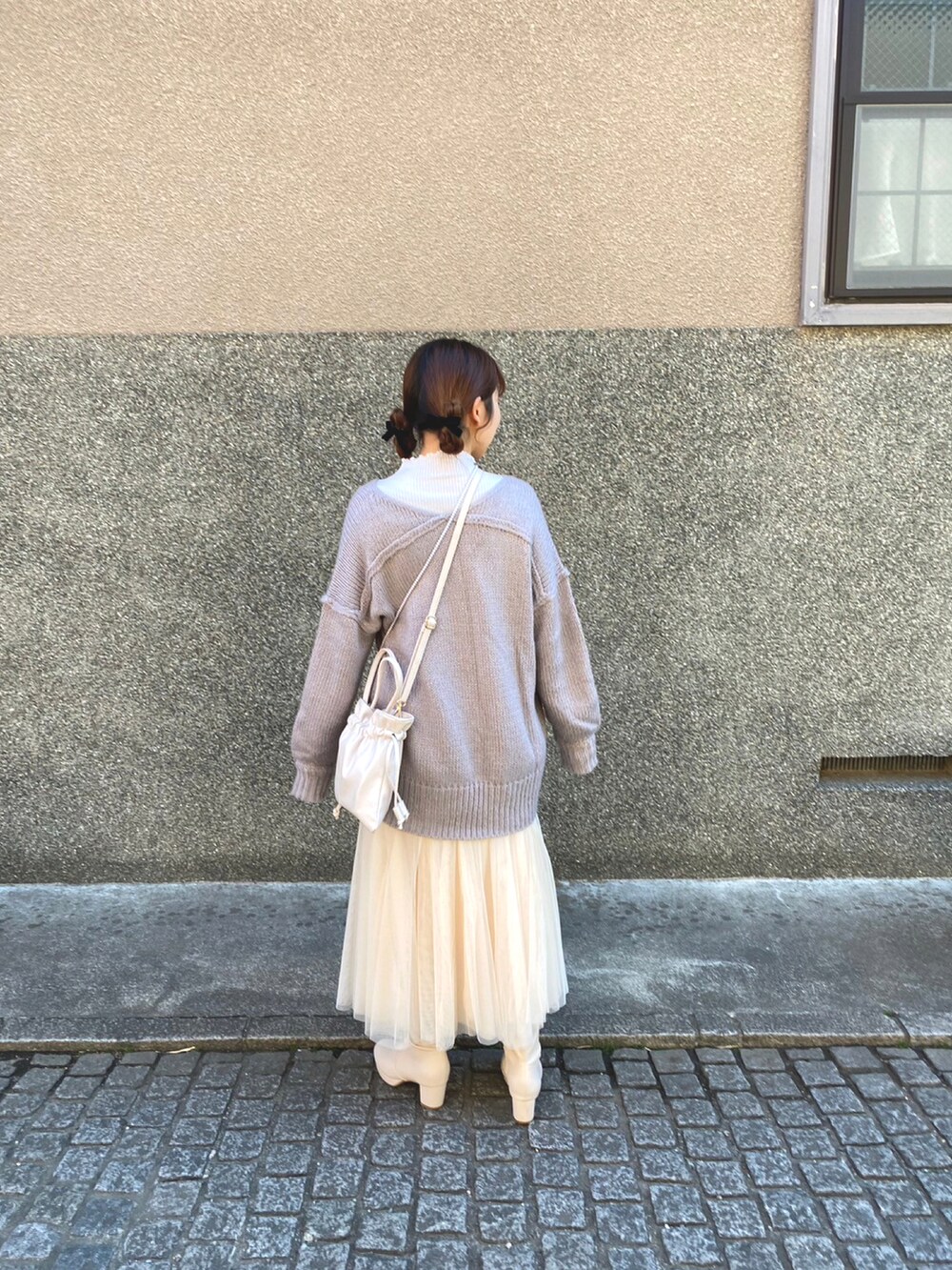 パープル系のニット/セーター、ホワイト系のスカート、ホワイト系のブーツを着用したレディースの春コーディネートの2枚目の写真