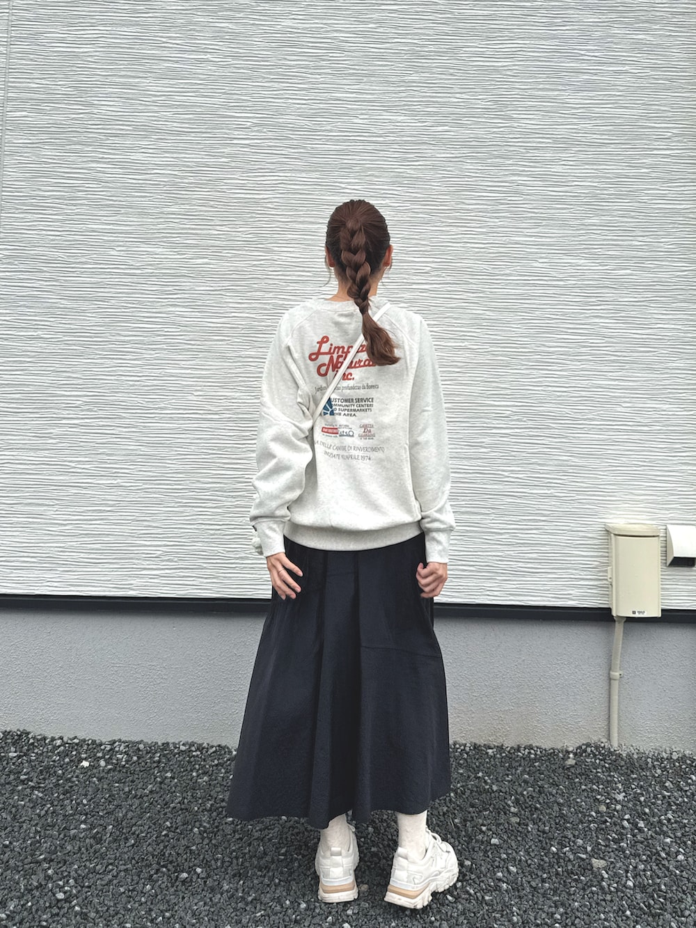 ブラック系のスカート、ベージュ系のスウェット、ホワイト系のショルダーバッグを着用したレディースの春コーディネートの2枚目の写真