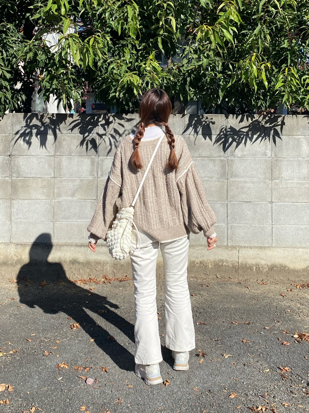 ホワイト系のショルダーバッグ、ベージュ系のカーディガン/ボレロ、ホワイト系のデニムパンツを着用したレディースの秋コーディネートの2枚目の写真