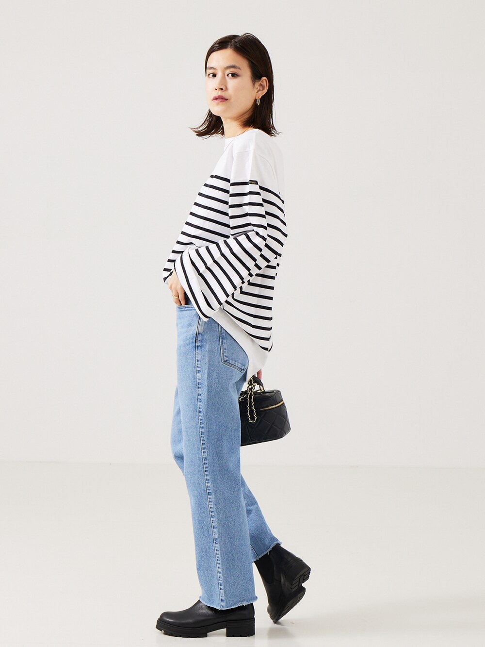ブルー系のデニムパンツ、ブラック系のブーツ、ホワイト系のTシャツ/カットソーを着用したレディースの秋コーディネートの2枚目の写真