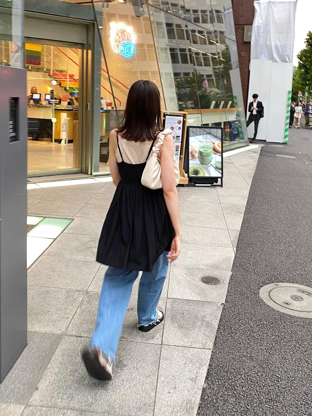 ブラック系のワンピース、ブルー系のデニムパンツを着用したレディースの春コーディネートの3枚目の写真