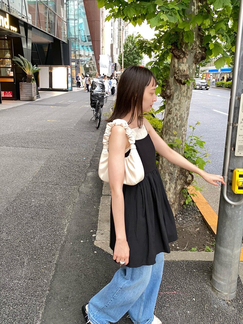 ブラック系のワンピース、ブルー系のデニムパンツを着用したレディースの春コーディネートの2枚目の写真