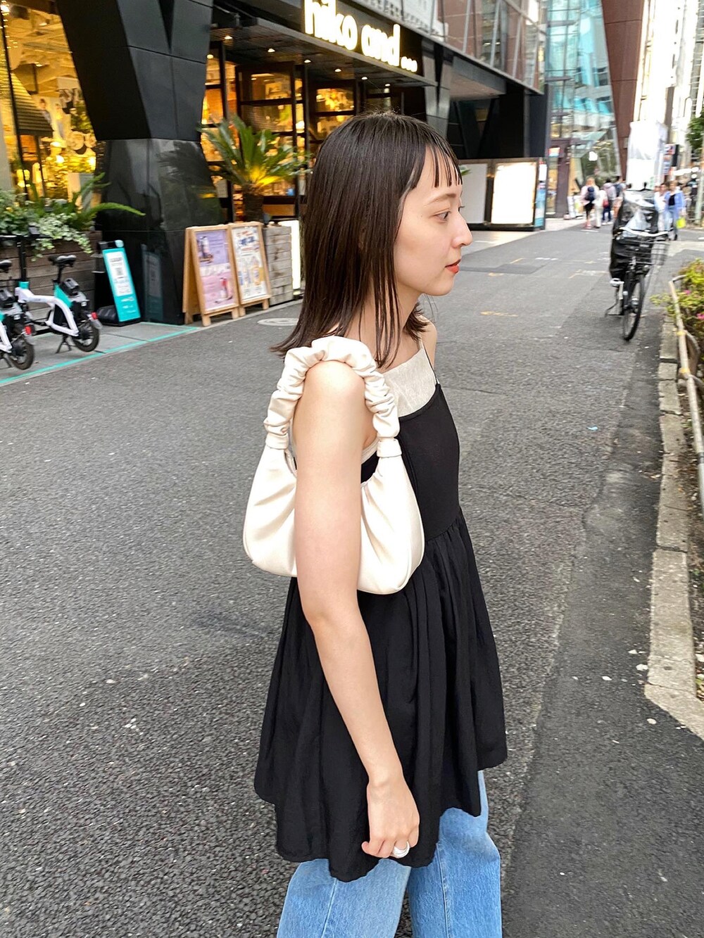 ブラック系のワンピース、ブルー系のデニムパンツを着用したレディースの春コーディネートの4枚目の写真