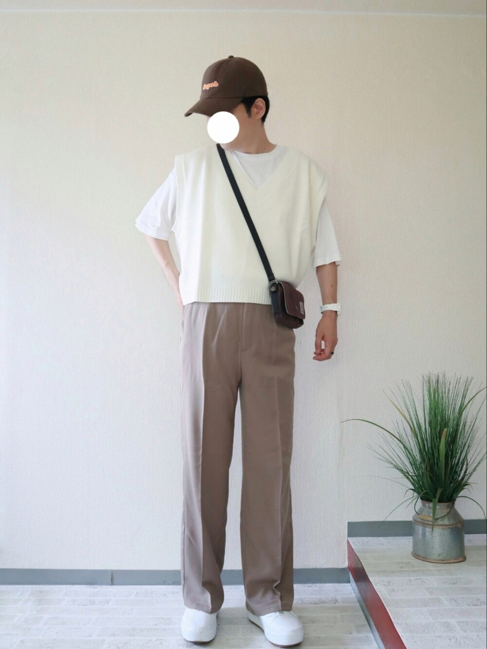 ベージュ系のスラックス、ホワイト系のベスト、レッド系のショルダーバッグを着用したメンズの夏コーディネートの3枚目の写真