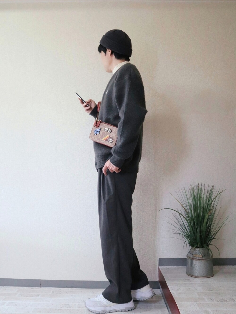 グリーン系のカーディガン/ボレロ、グレー系のその他パンツ、ブラウン系のショルダーバッグを着用したメンズの秋コーディネートの2枚目の写真