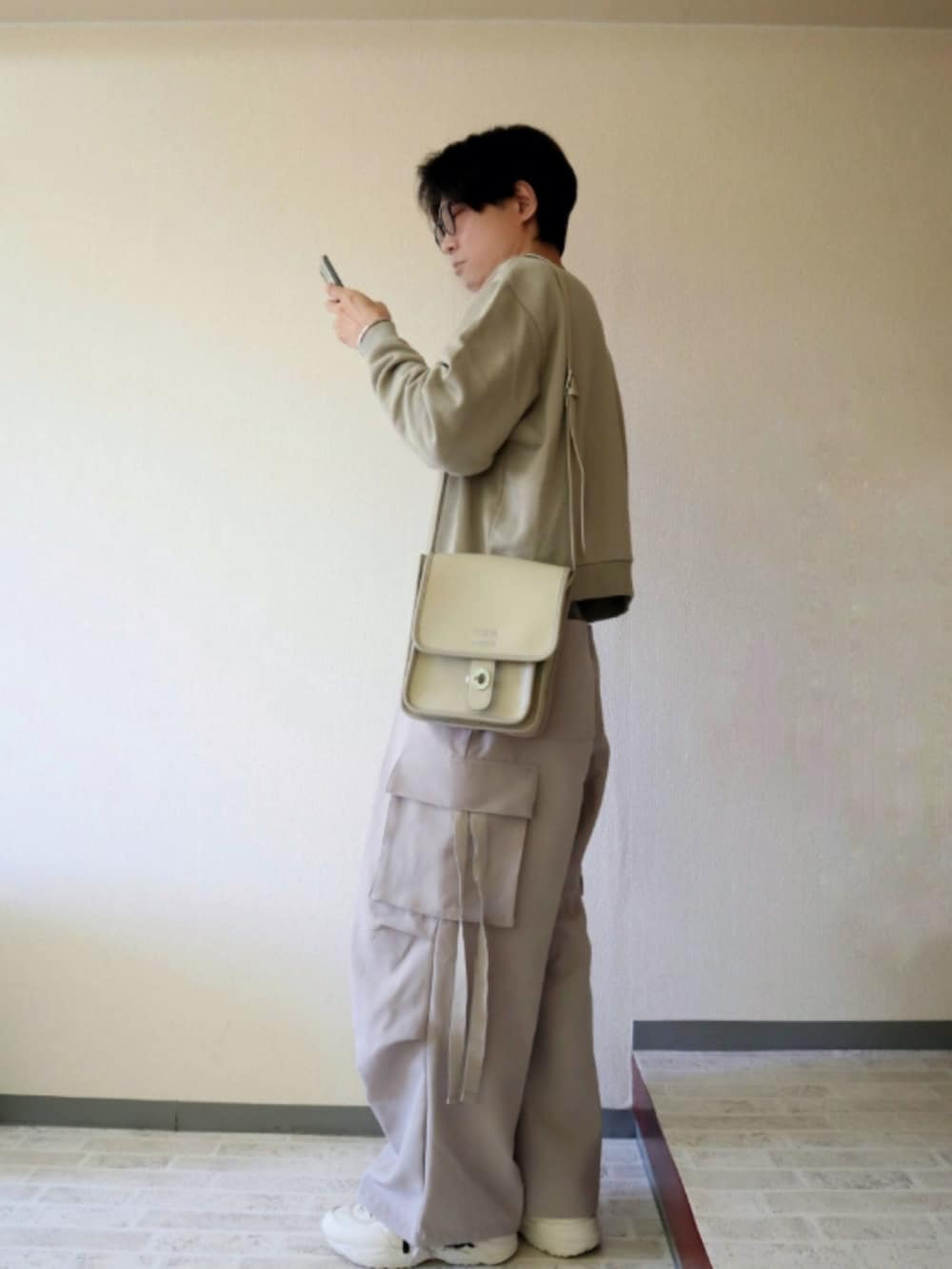 グリーン系のスウェット、グレー系のカーゴパンツ、ベージュ系のスニーカーを着用したメンズの秋コーディネートの2枚目の写真