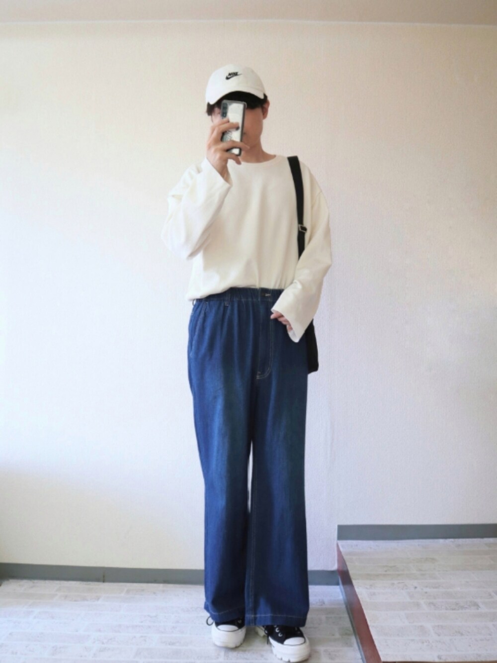 ブルー系のデニムパンツ、ホワイト系のTシャツ/カットソー、ブラック系のショルダーバッグを着用したメンズの春コーディネートの2枚目の写真