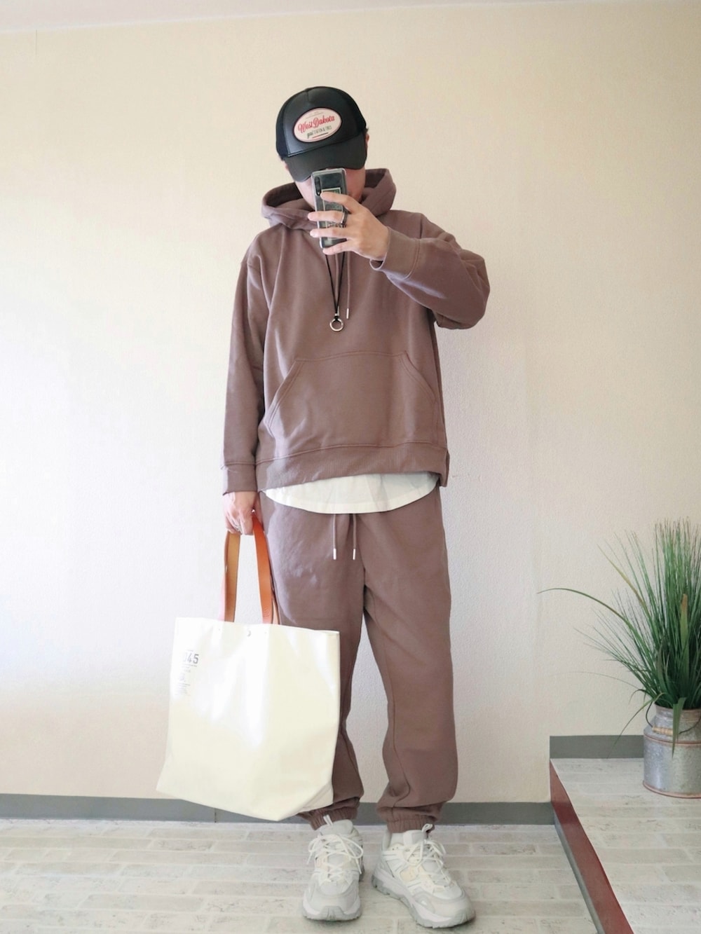 ベージュ系のパーカー、ベージュ系のスウェットパンツ、ホワイト系のトートバッグを着用したメンズの秋コーディネートの3枚目の写真