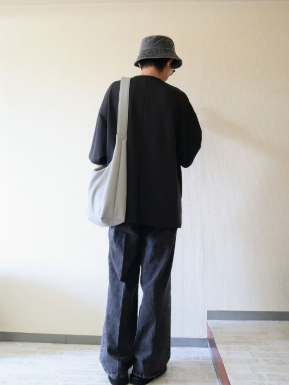 グレー系のデニムパンツ、グレー系のTシャツ/カットソー、ブラック系のサンダルを着用したメンズの夏コーディネートの2枚目の写真