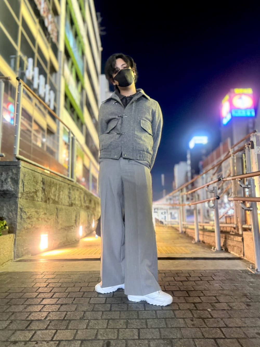 グレー系のブルゾン、グレー系のスラックス、ホワイト系のスニーカーを着用したメンズの冬コーディネートの2枚目の写真