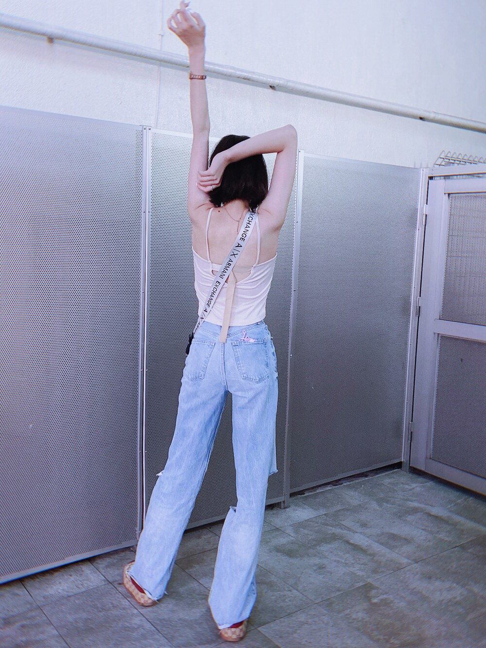 ホワイト系のキャミソール、ブルー系のショルダーバッグ、ブルー系のデニムパンツを着用したレディースの夏コーディネートの2枚目の写真