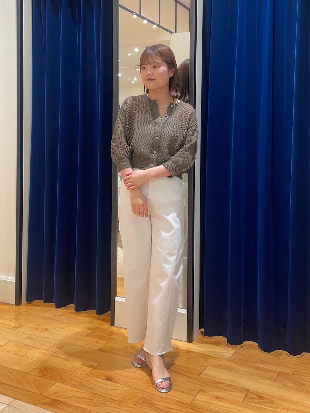 ホワイト系のデニムパンツ、シルバー系のサンダル、ブラウン系のカーディガン/ボレロを着用したレディースの春コーディネートの2枚目の写真