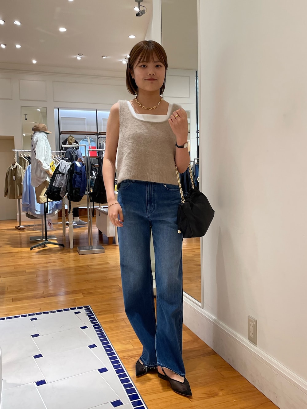 ブルー系のデニムパンツ、イエロー系のベスト、ホワイト系のタンクトップを着用したレディースの夏コーディネートの2枚目の写真