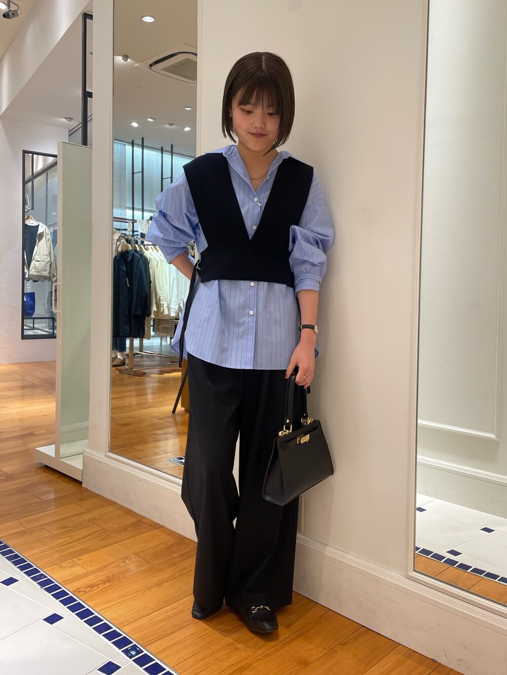 ブラック系のニット/セーター、ブルー系のシャツ/ブラウス、ブラック系のその他パンツを着用したレディースの冬コーディネートの2枚目の写真