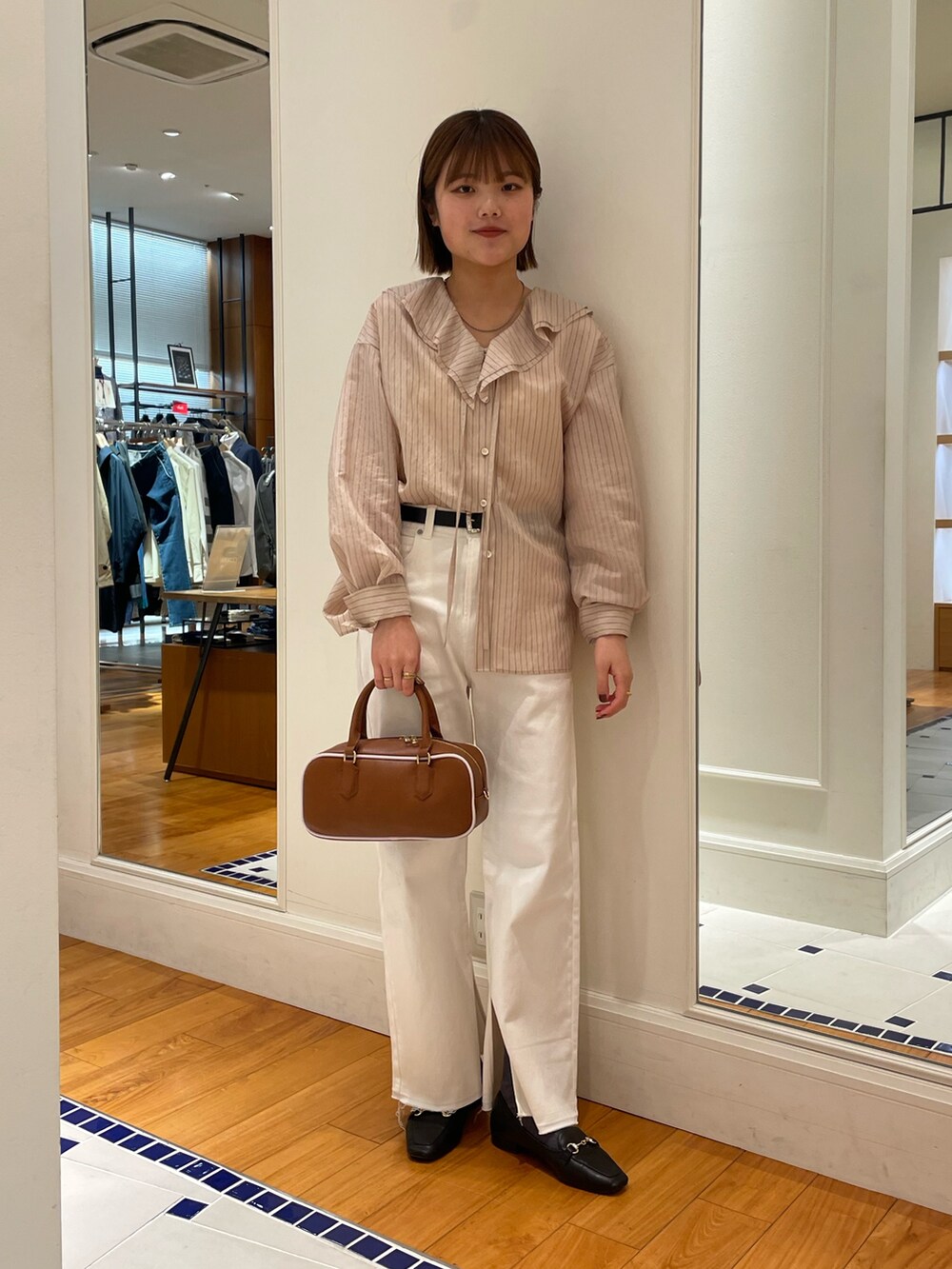 ベージュ系のシャツ/ブラウス、ホワイト系のデニムパンツ、イエロー系のボストンバッグを着用したレディースの冬コーディネートの2枚目の写真