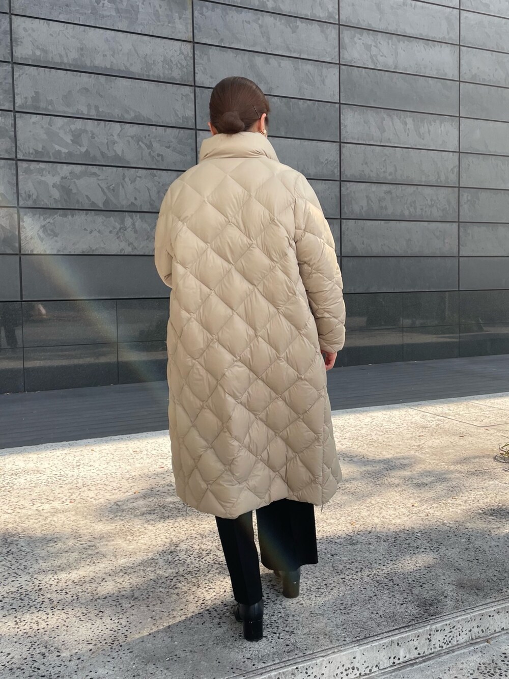 ホワイト系のニット/セーター、ブラック系のその他パンツ、ベージュ系のダウンジャケット/コートを着用したレディースの秋コーディネートの4枚目の写真