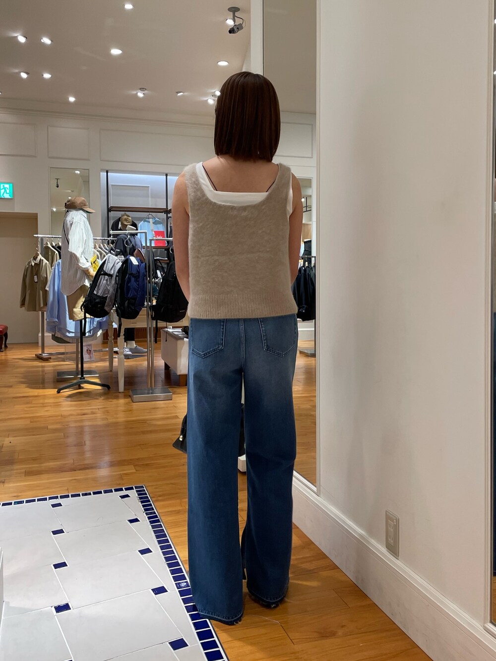 ブルー系のデニムパンツ、イエロー系のベスト、ホワイト系のタンクトップを着用したレディースの夏コーディネートの4枚目の写真