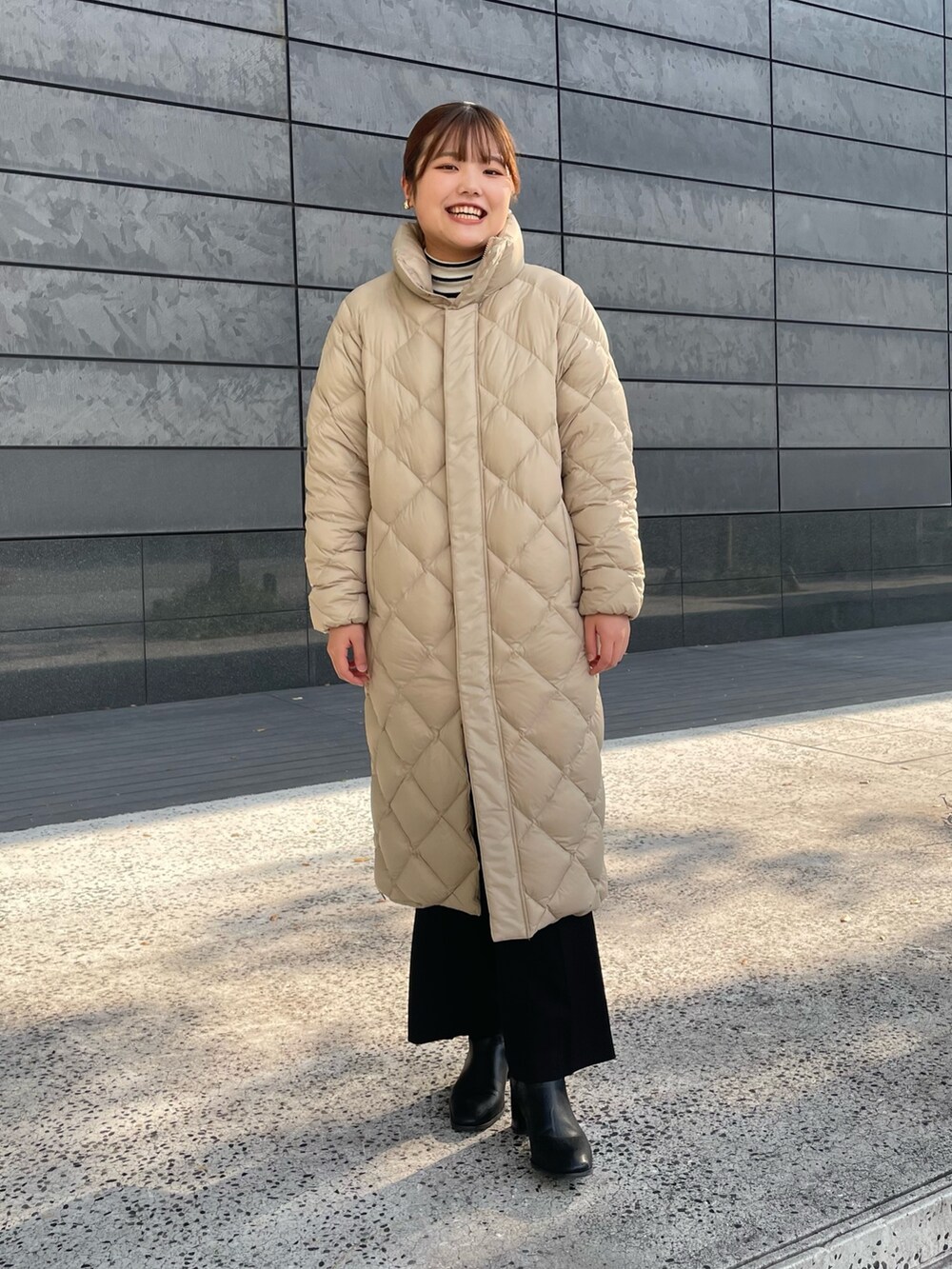 ホワイト系のニット/セーター、ブラック系のその他パンツ、ベージュ系のダウンジャケット/コートを着用したレディースの秋コーディネートの2枚目の写真