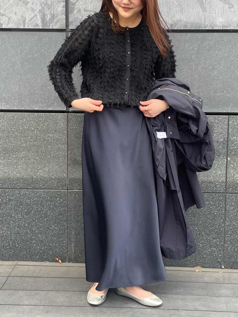 ブルー系のスカート、ブラック系のカーディガン/ボレロ、ブラック系のタンクトップを着用したレディースの春コーディネートの2枚目の写真