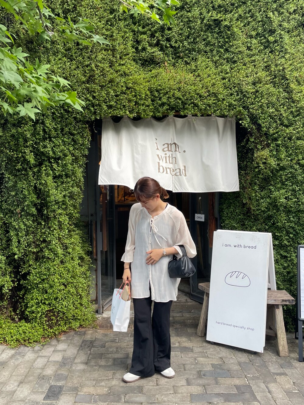 ホワイト系のトップス、ブラック系のパンツ、ブラック系のショルダーバッグを着用したレディースの夏コーディネートの4枚目の写真